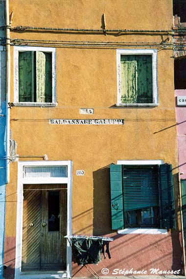 Laundry drying in front of a yellow house in Burano